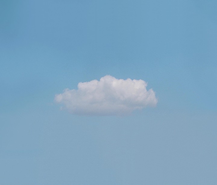A single white cloud floats in a clear blue sky.