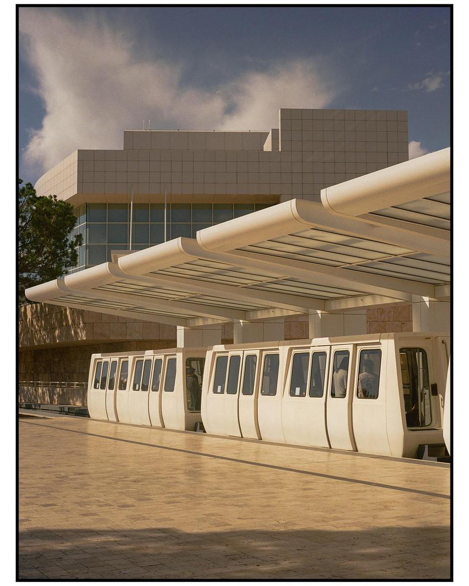 A monorail train is parked at a station with a modern building in the background.