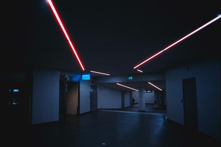 Red neon lights illuminate a dark subway station.