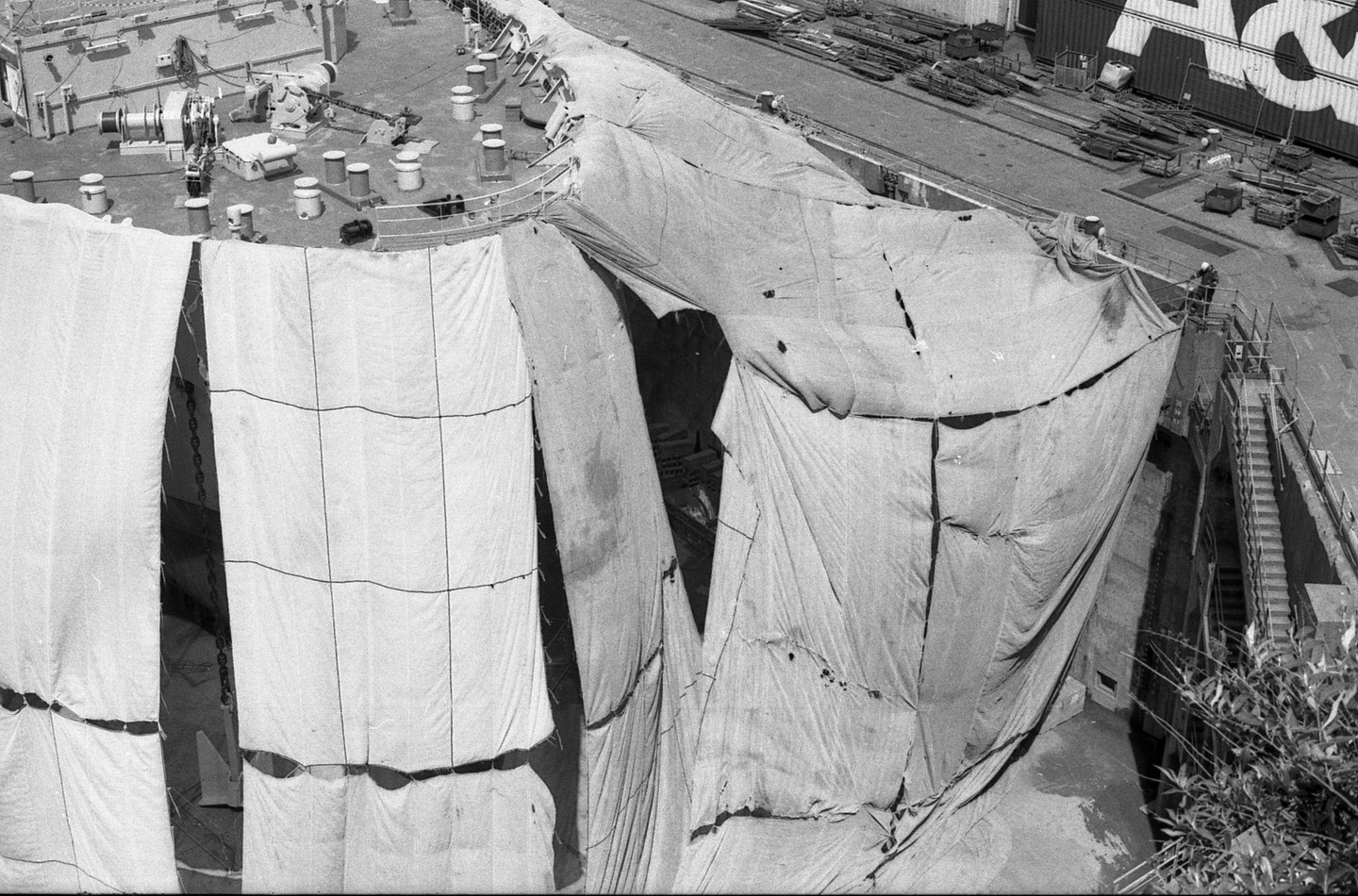 A ship is covered with large tarps while docked at a port.