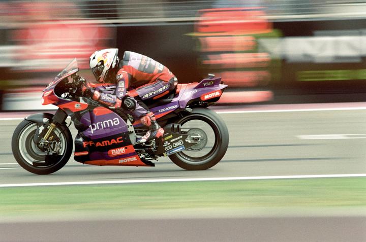 A person on a motorcycle races on a track.