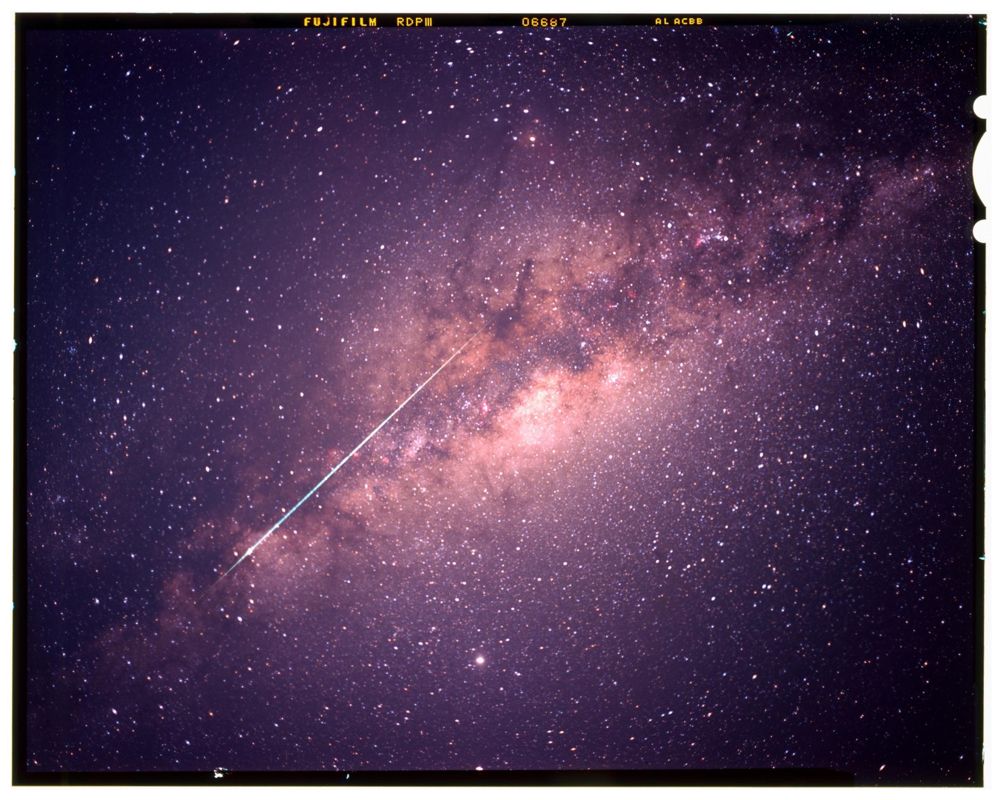 A meteor streaks across a night sky filled with stars and the Milky Way.