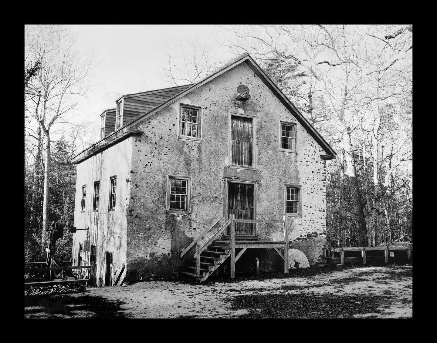 A large, old, stone building with a wooden staircase leading to its entrance stands among bare trees.