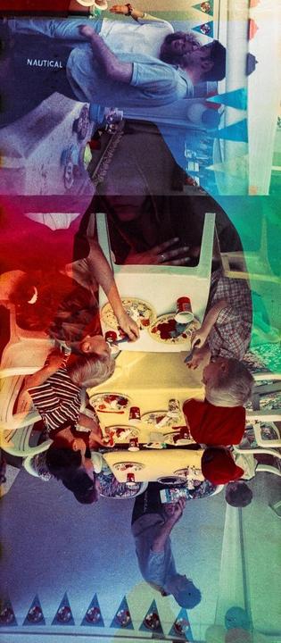 A double exposure shows a man and children at a birthday party with colorful banners.