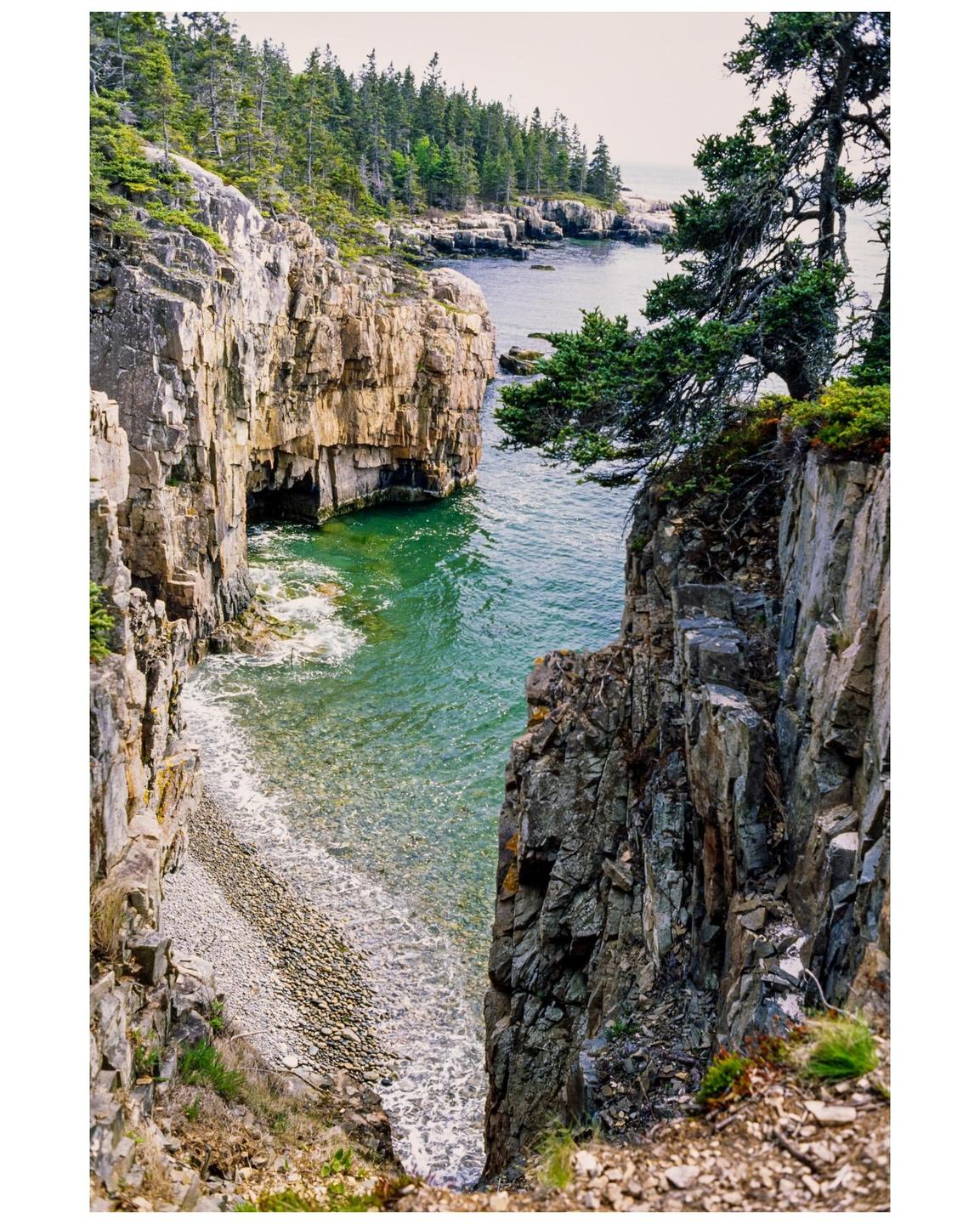 A narrow inlet with rocky cliffs and evergreen trees on the coastline of Schoodic Peninsula.