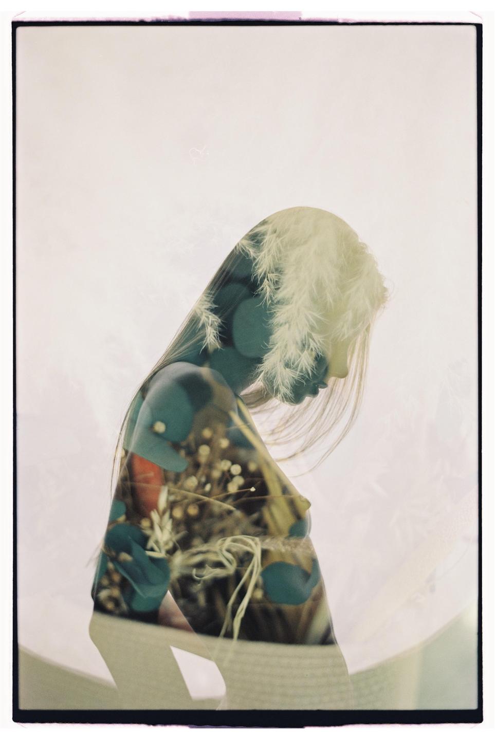 A double exposure shows the silhouette of a woman with long hair overlaid with an image of plants and flowers.