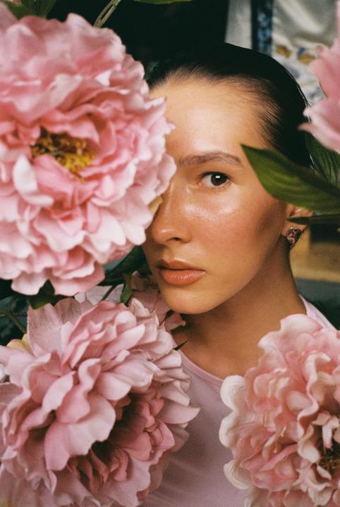 A woman's face is framed by large pink flowers.