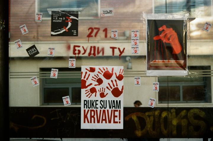 A storefront window is covered with protest posters and graffiti.