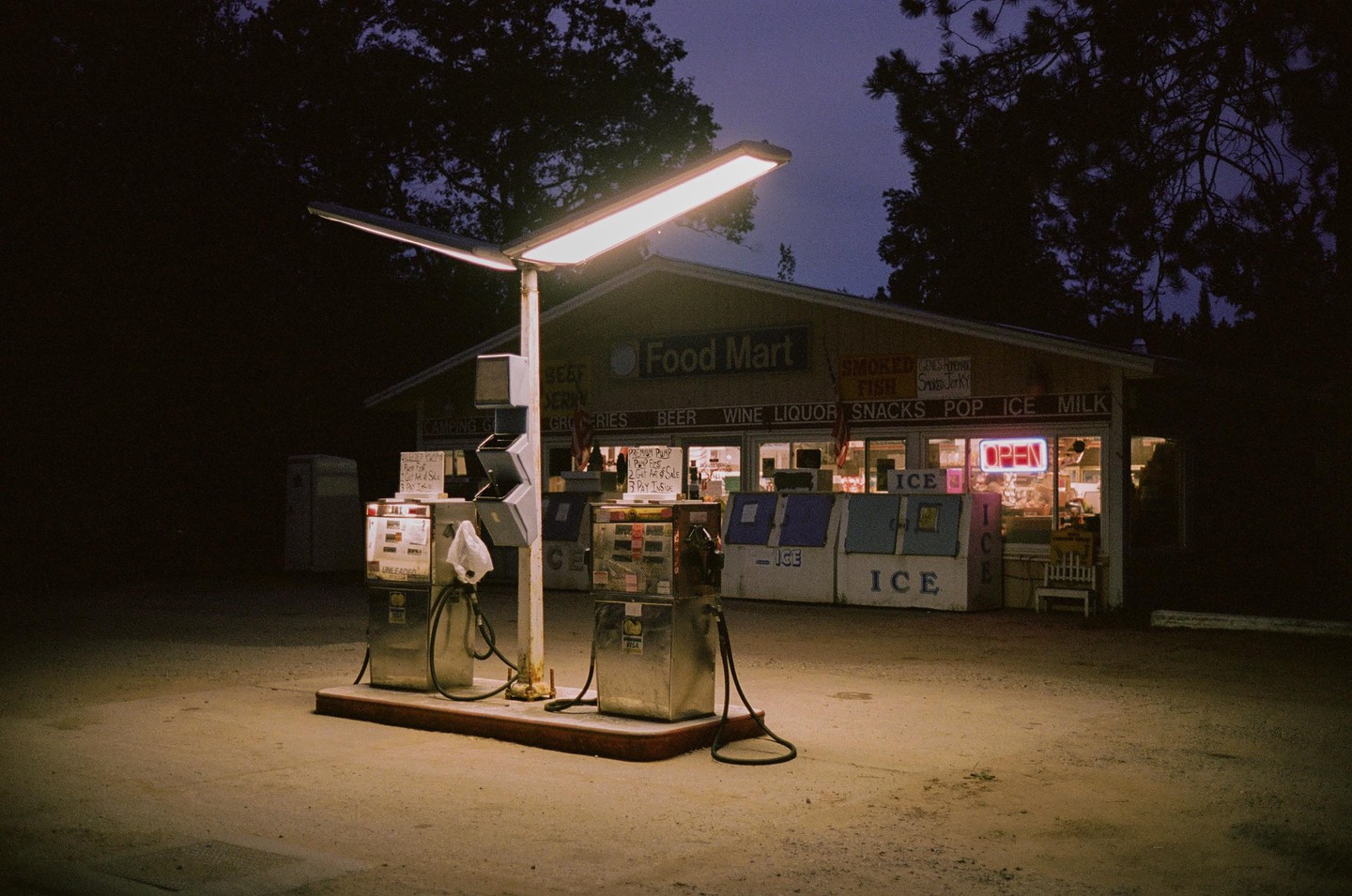 A gas station and convenience store are illuminated at night.