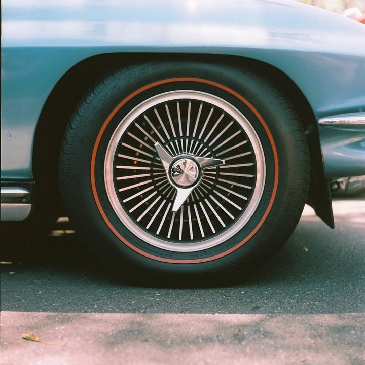 A close-up shot shows the wheel and fender of a vintage car.