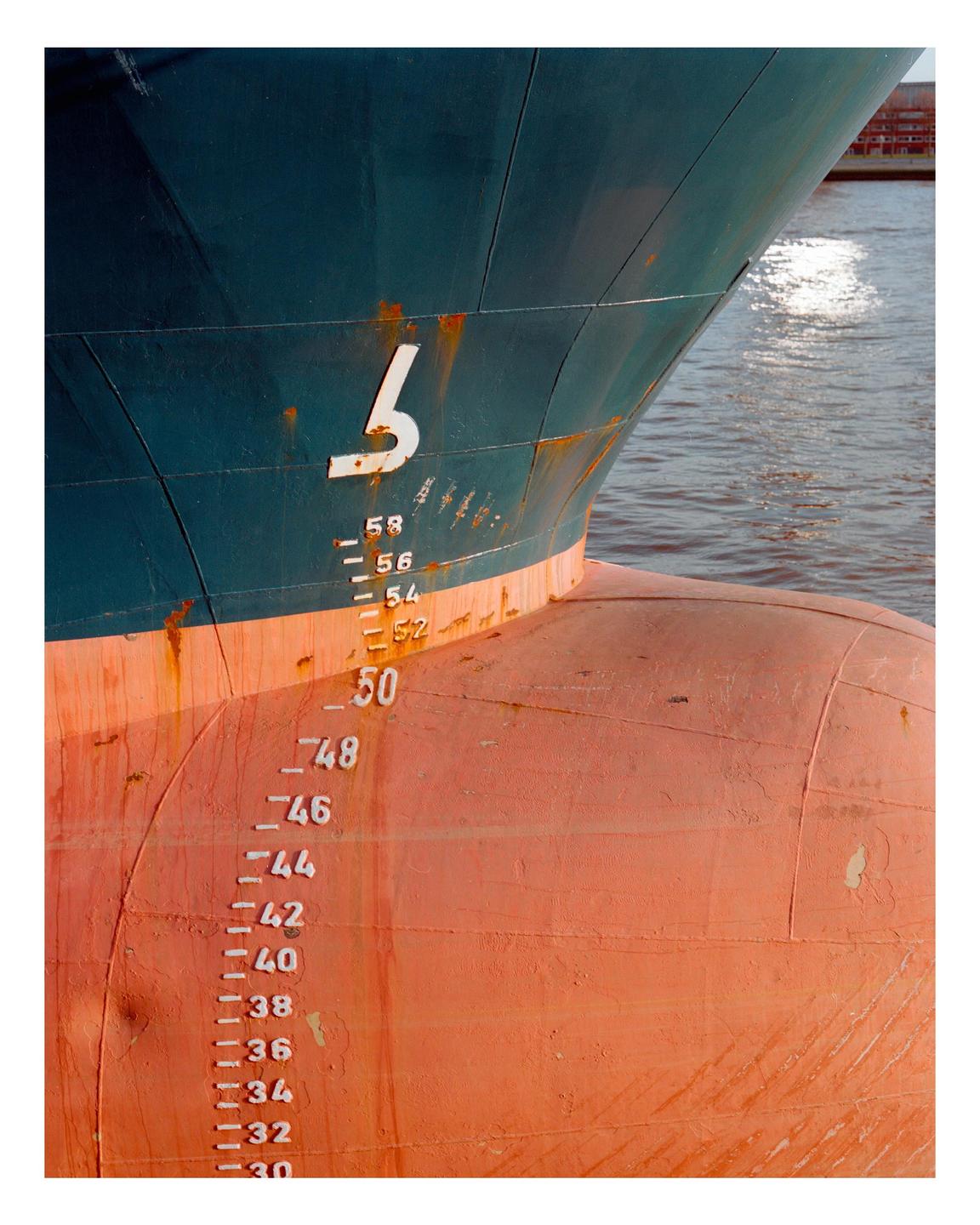 The bow of a large ship with draft markings is visible above the water.