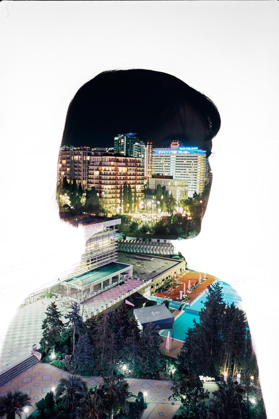 A double exposure shows a woman's silhouette filled with a night cityscape and a resort with swimming pools.