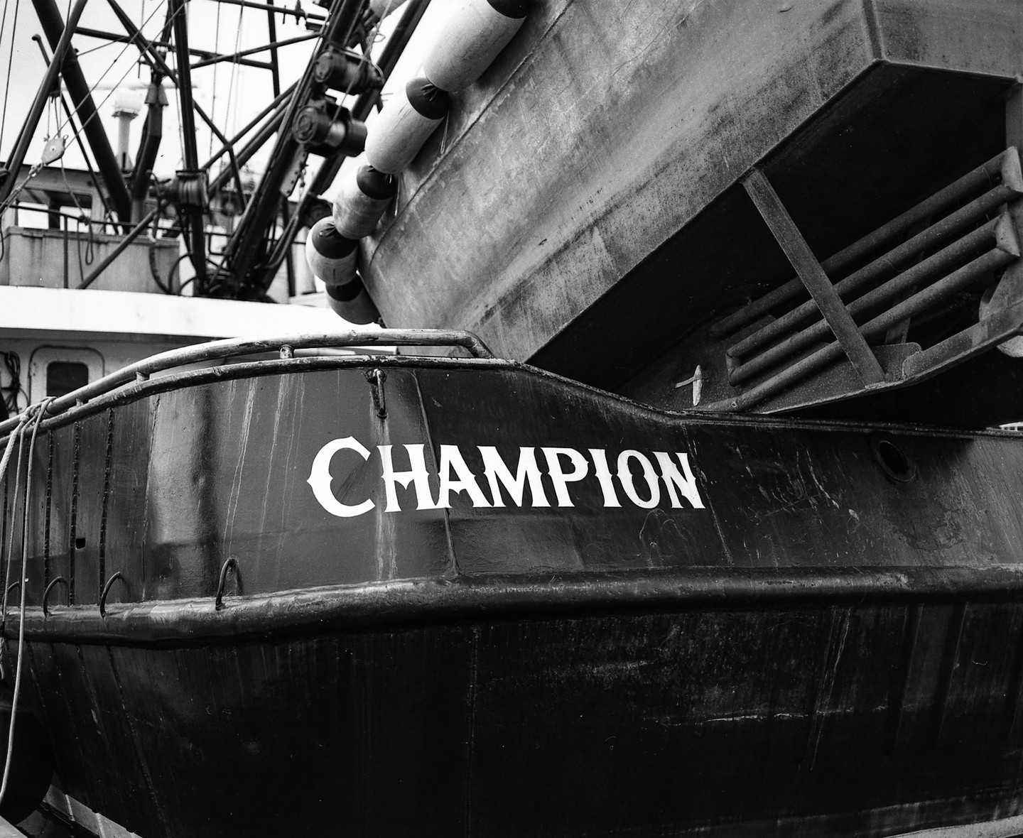 The stern of a fishing boat named Champion is visible with buoys hanging from the side.
