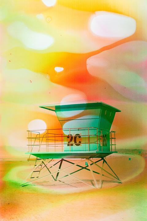 A green lifeguard stand with the number 2C is visible on a beach under a bright, colorful sky.