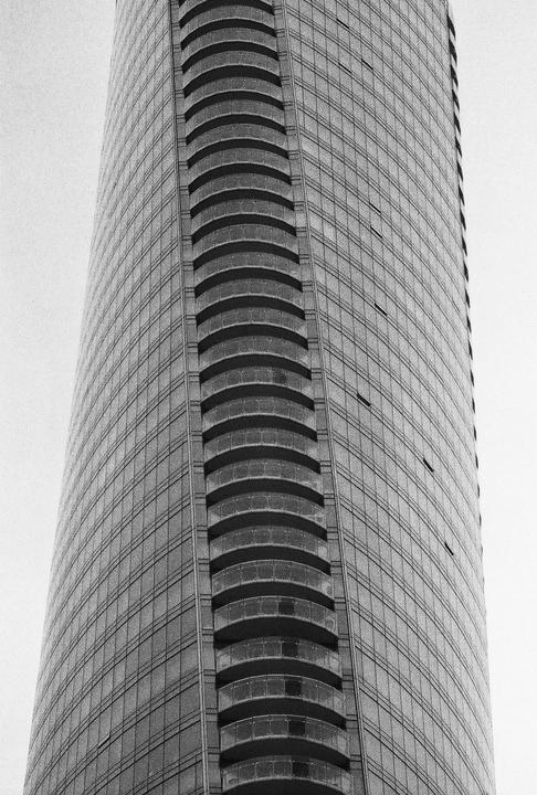 A tall building with many windows and curved balconies is shown from a low angle.