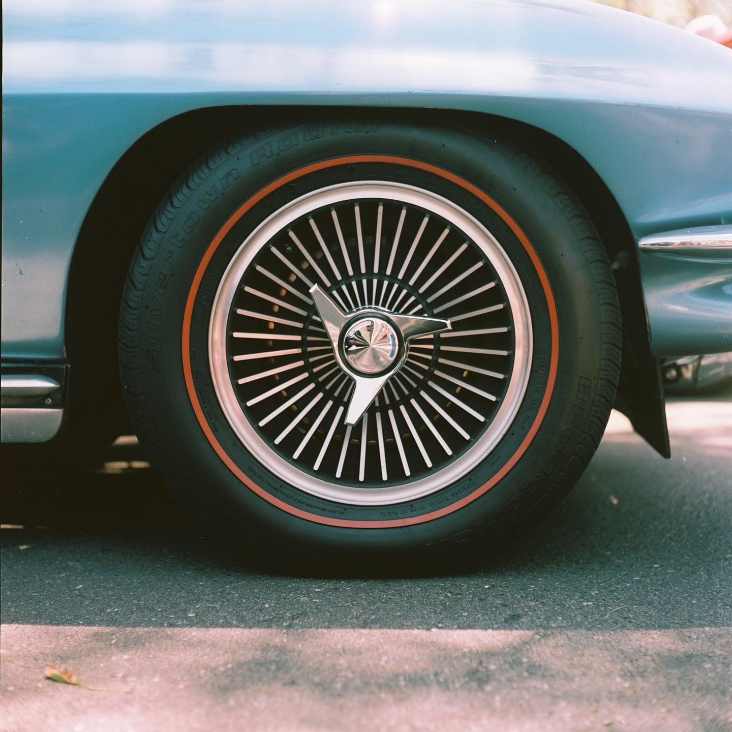 A close-up shot shows the wheel and fender of a vintage car.