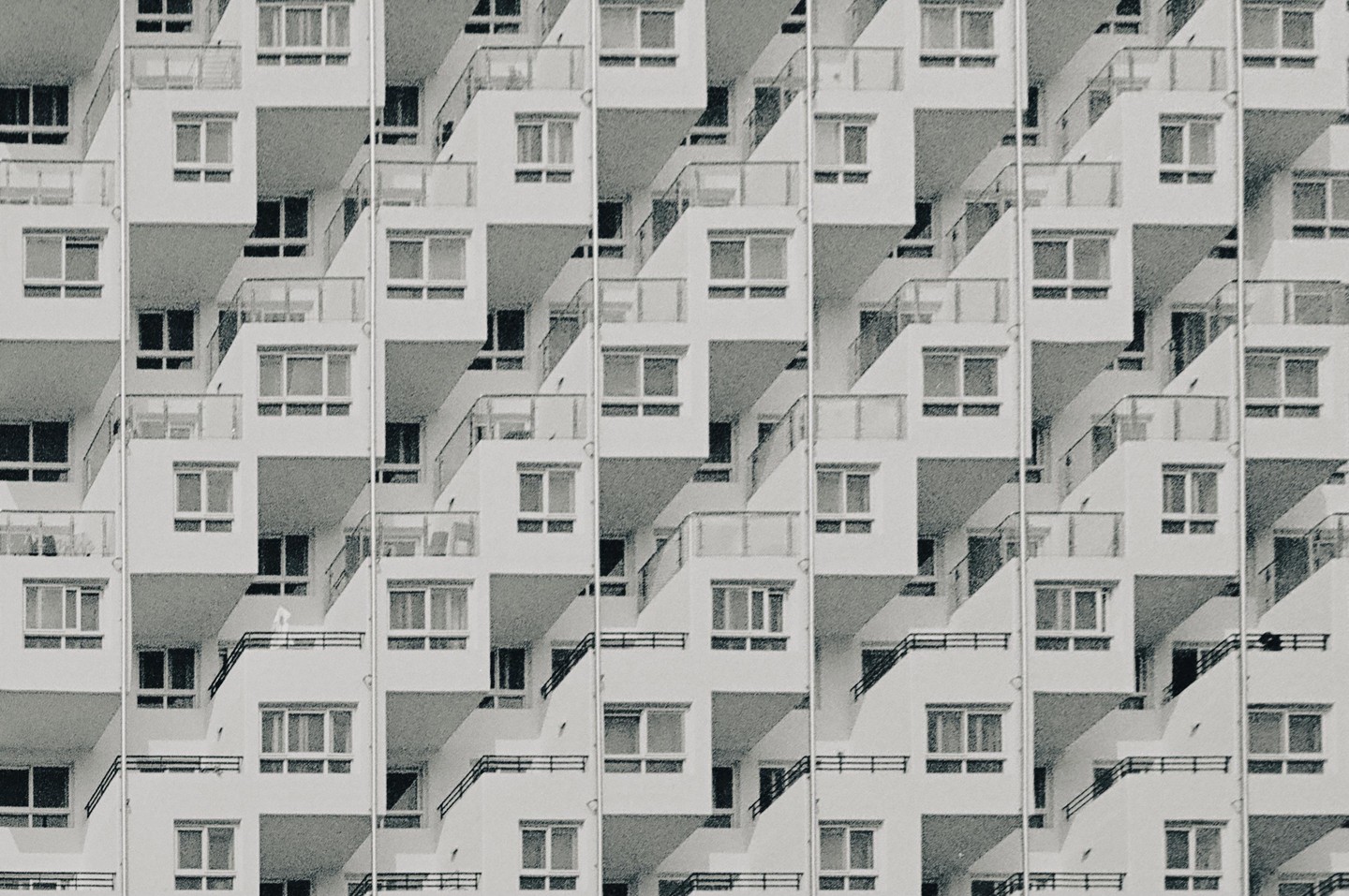 A repeating pattern of apartment building balconies and windows creates an abstract composition.