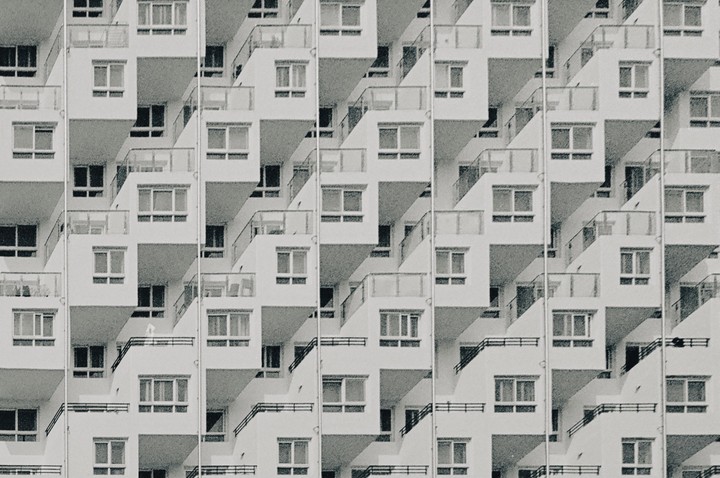 A repeating pattern of apartment building balconies and windows creates an abstract composition.