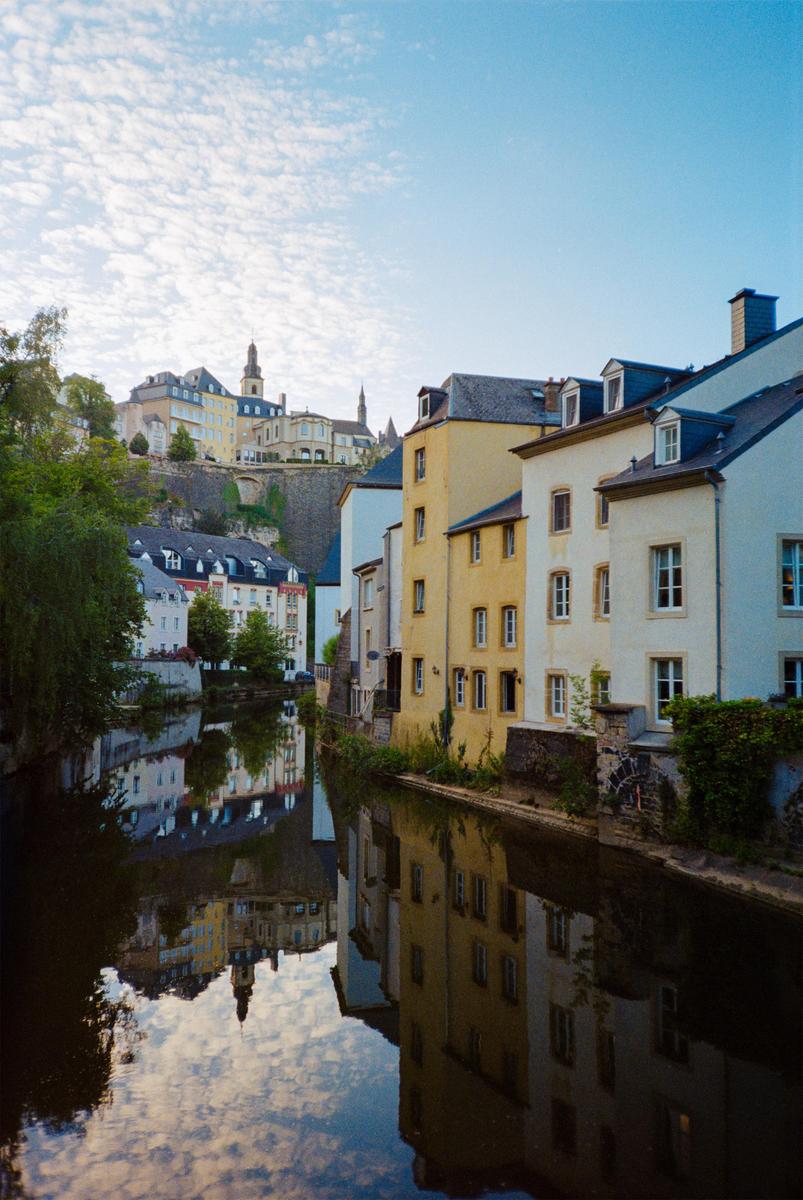 A canal with buildings on both sides reflects the sky and structures in its still water.