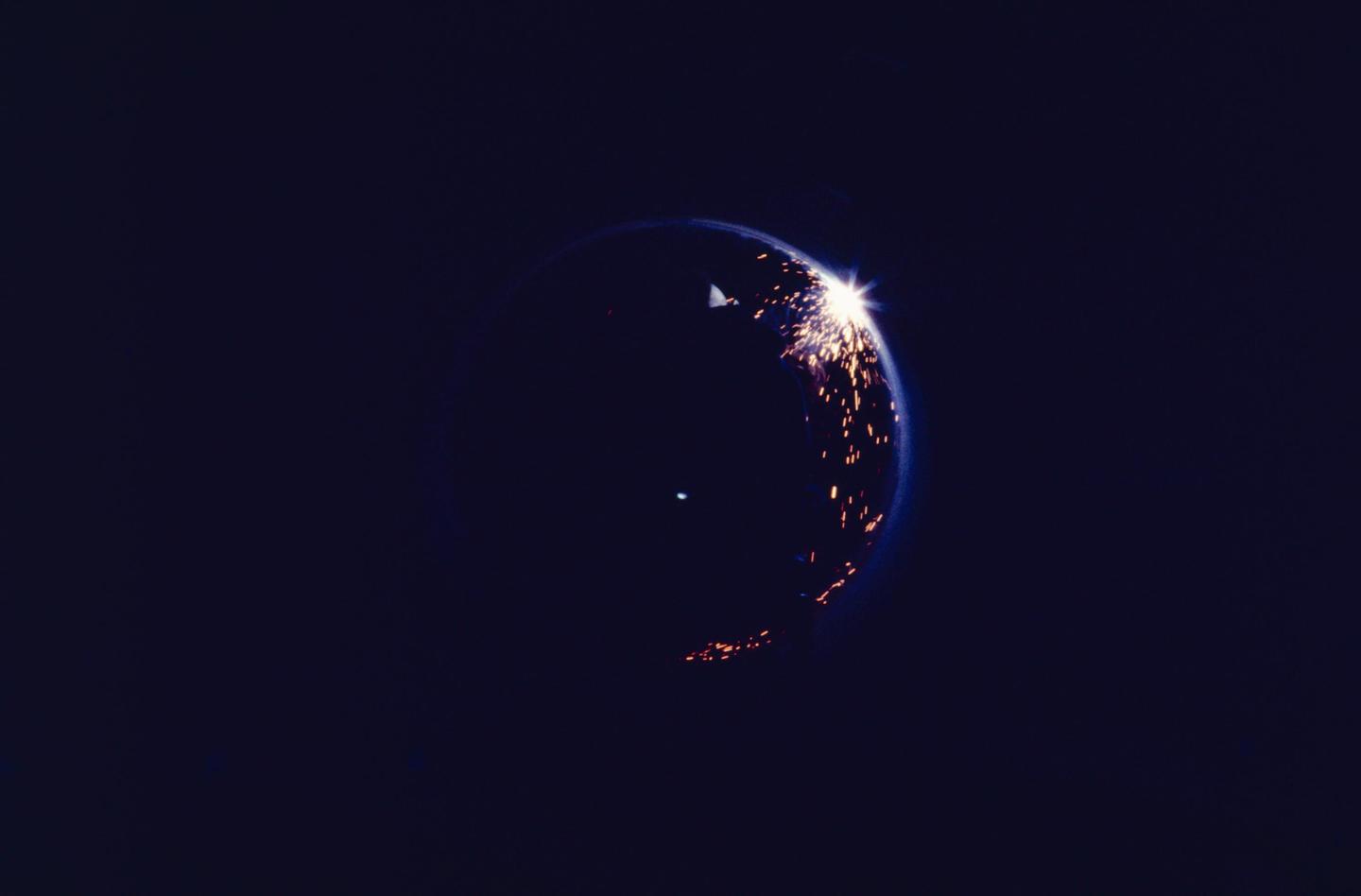 A welder works on the Trans Alaska Pipeline, creating bright sparks against a dark background.