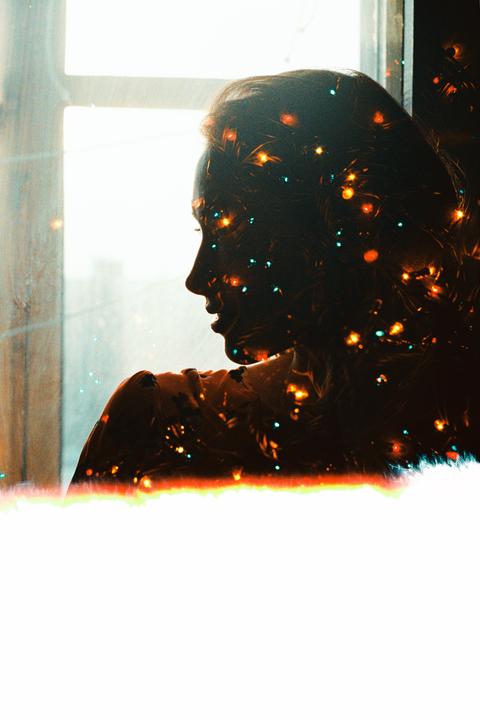 A woman's silhouette is visible in profile, filled with colorful bokeh lights, against a bright window.