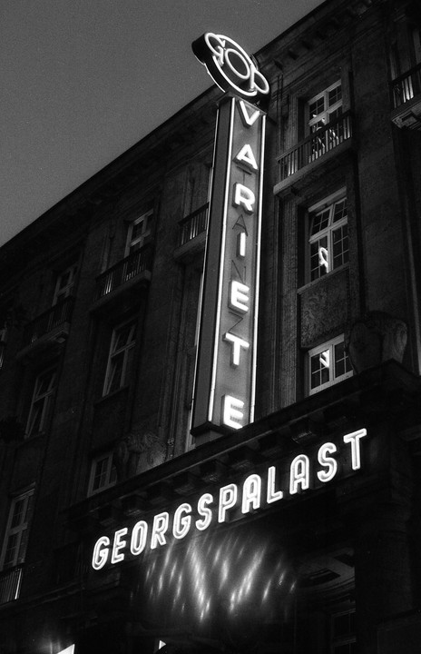 A neon sign for "Variete Georgspalast" illuminates a building at night.