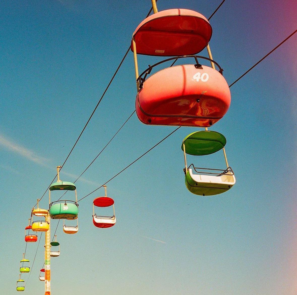 Colorful gondolas hang from cables against a clear blue sky.