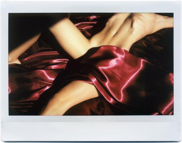 A person's body is partially covered by a red satin sheet.