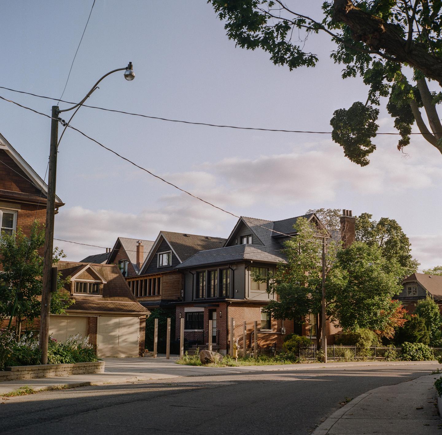 A street with houses and trees is visible under a partly cloudy sky.