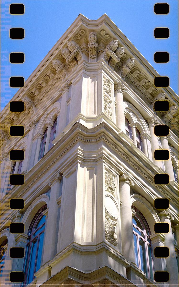 A low-angle view shows the ornate corner of a building against a clear blue sky.