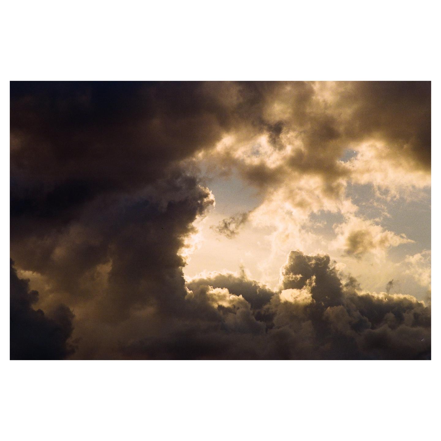 Dark storm clouds are illuminated from behind by a bright sky.