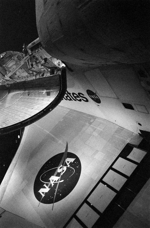 A black and white image shows the side of a space shuttle with the NASA logo and the word "States" visible.