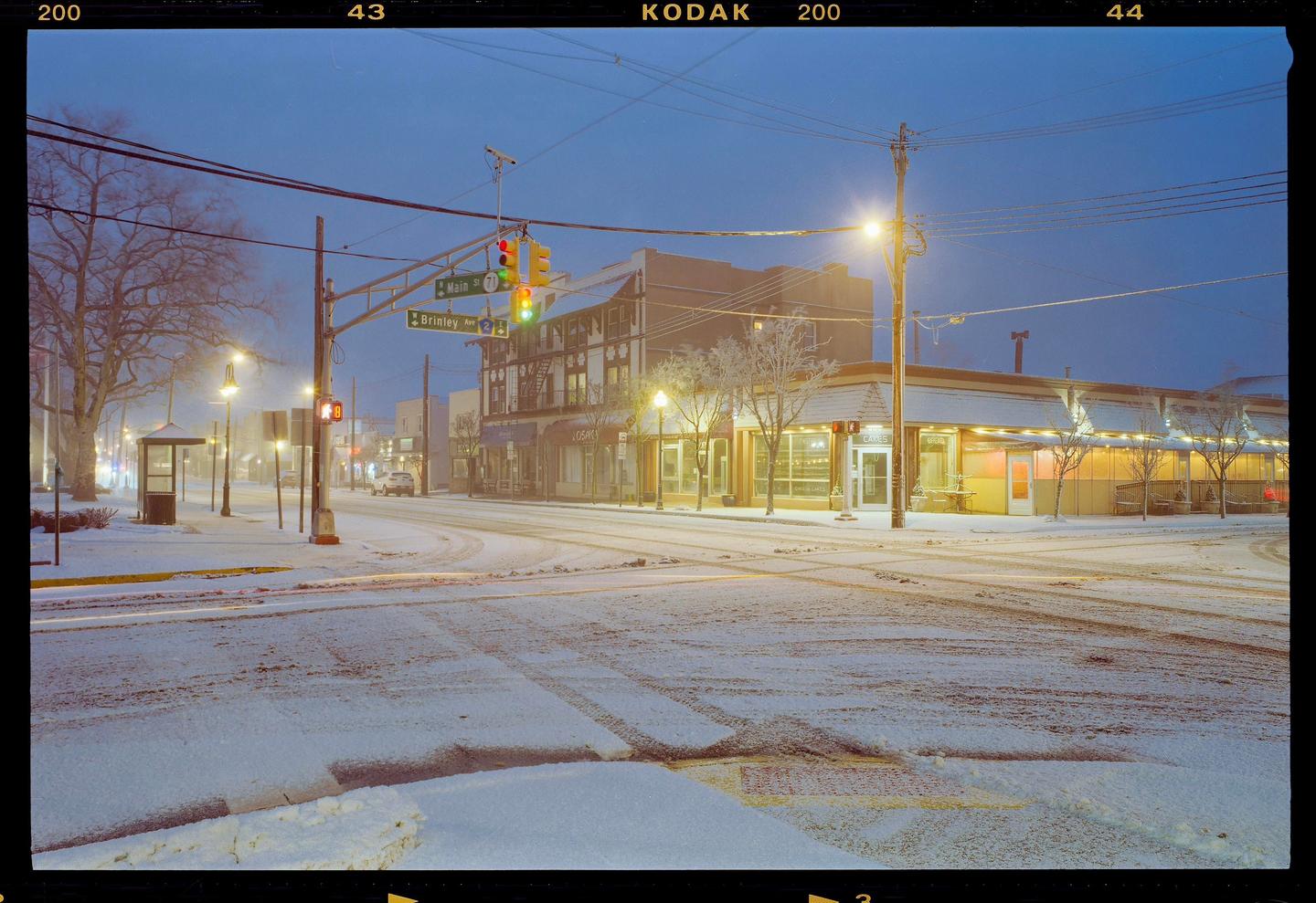 A snow-covered street corner with buildings and streetlights is visible at night.