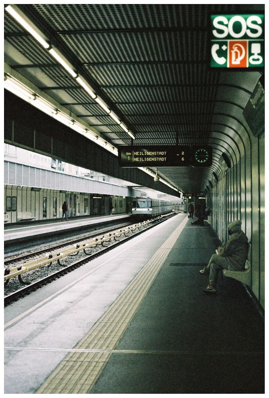 A person sits on a bench at a subway station as a train approaches.
