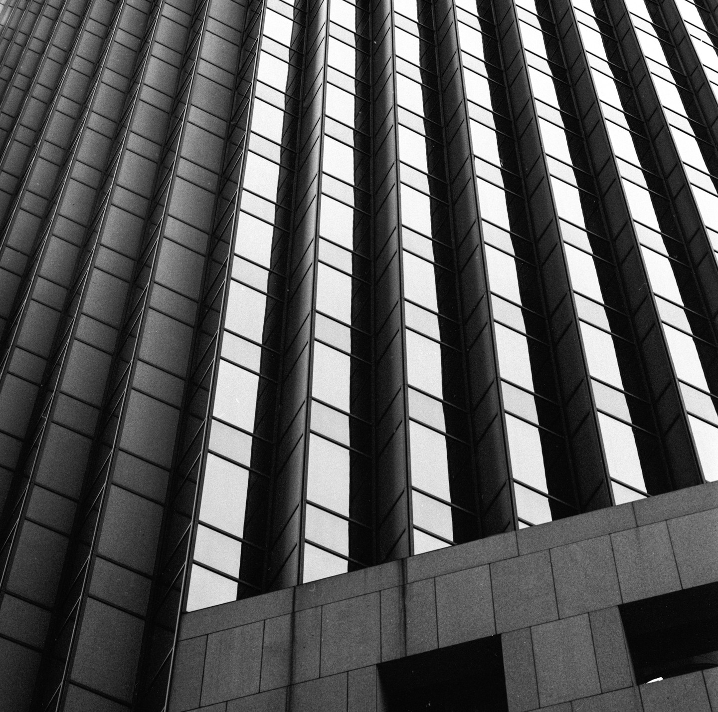 A low-angle view shows the facade of a modern building with vertical stripes of windows and dark panels.