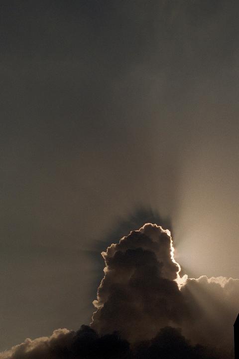 Sunlight shines from behind a large cloud, creating crepuscular rays.