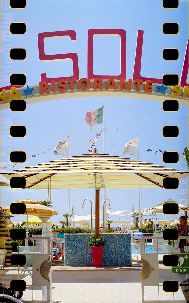 A large sign for "SOL RISTORANTE" is visible above a beach club entrance with umbrellas and an Italian flag.
