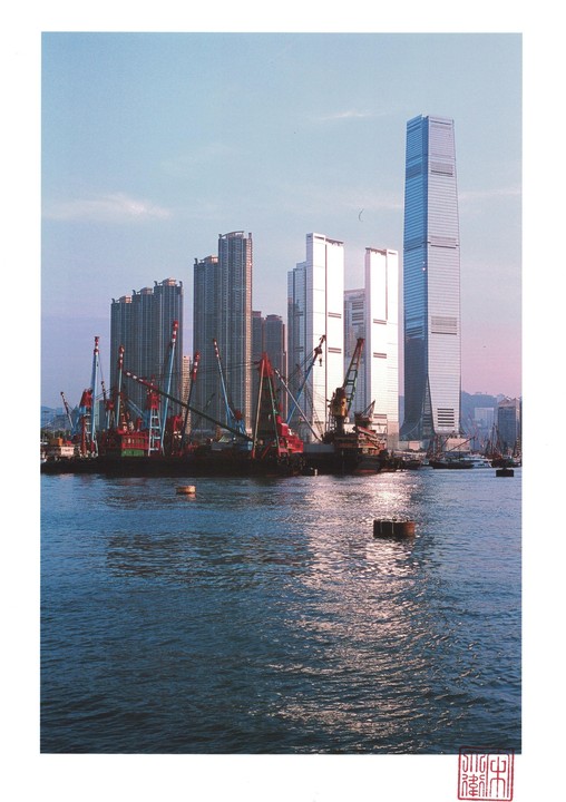 A cityscape with many tall buildings and construction barges on the water is visible at sunset.