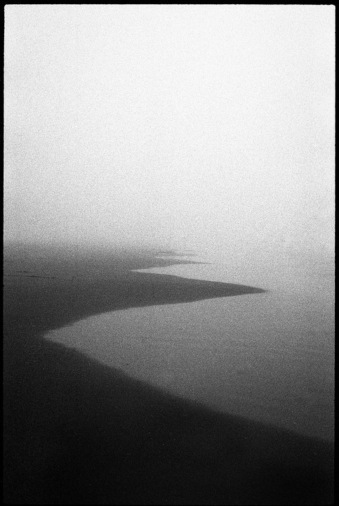 A winding shadow stretches across a hazy, bright landscape.