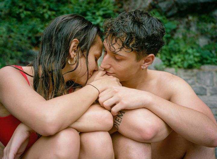 A couple with wet hair is embracing each other with their eyes closed.