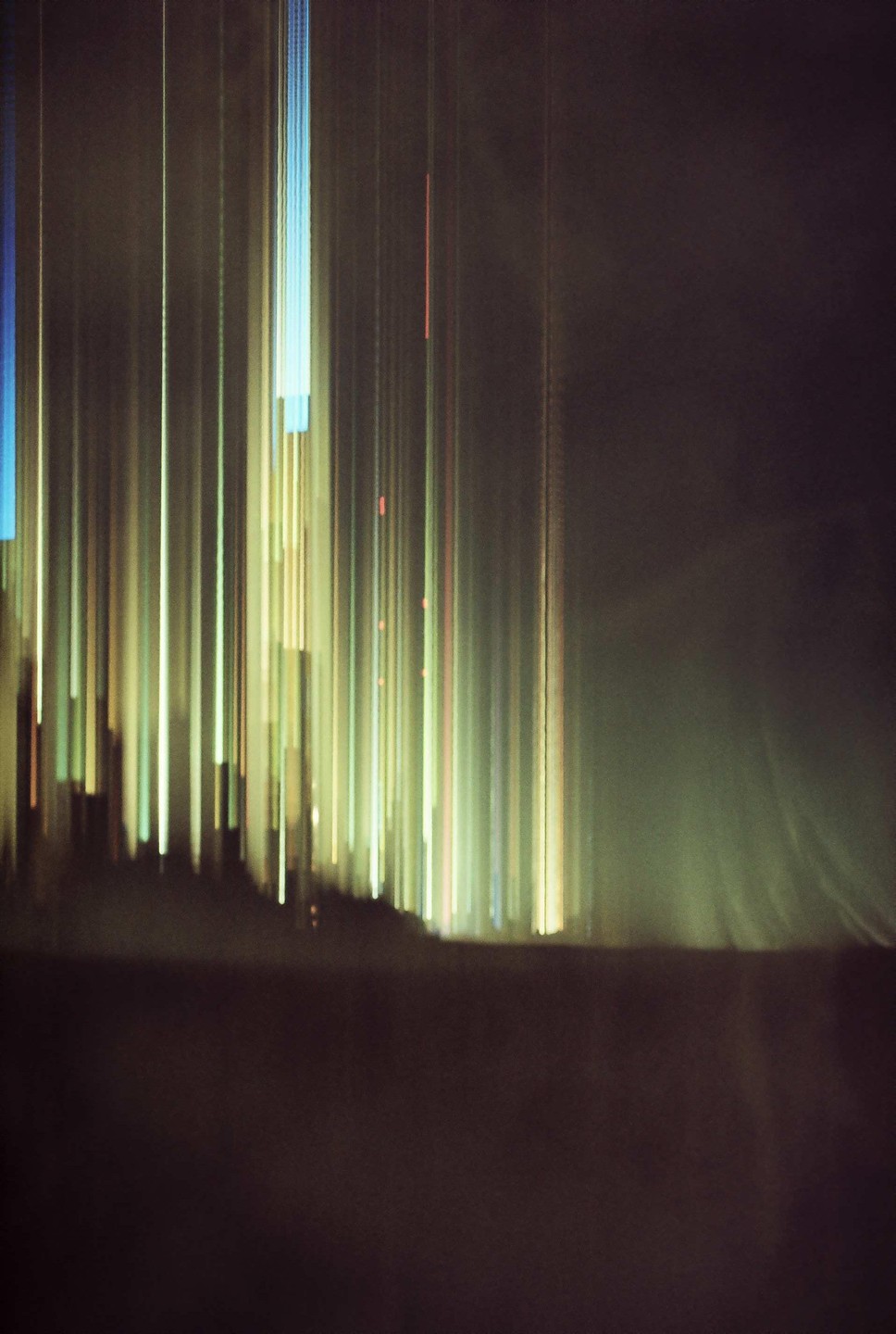 Vertical streaks of light in various colors appear against a dark background.