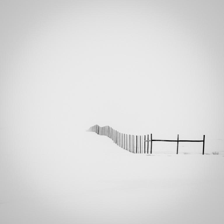 A fence extends into the distance across a snow-covered landscape.