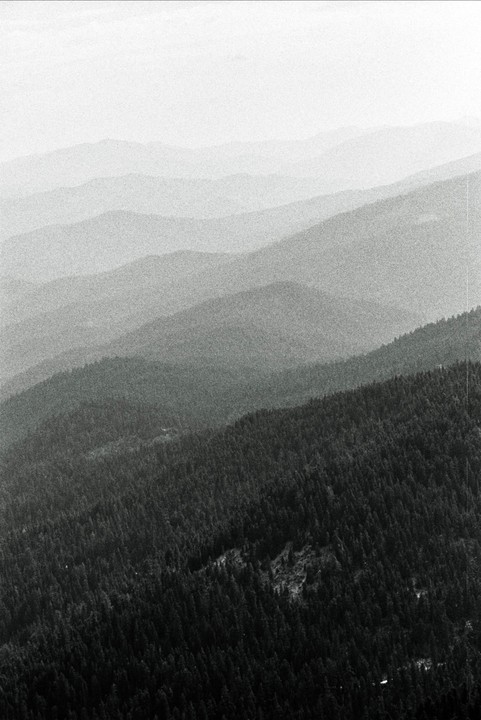 A hazy landscape shows layers of forested mountains receding into the distance.