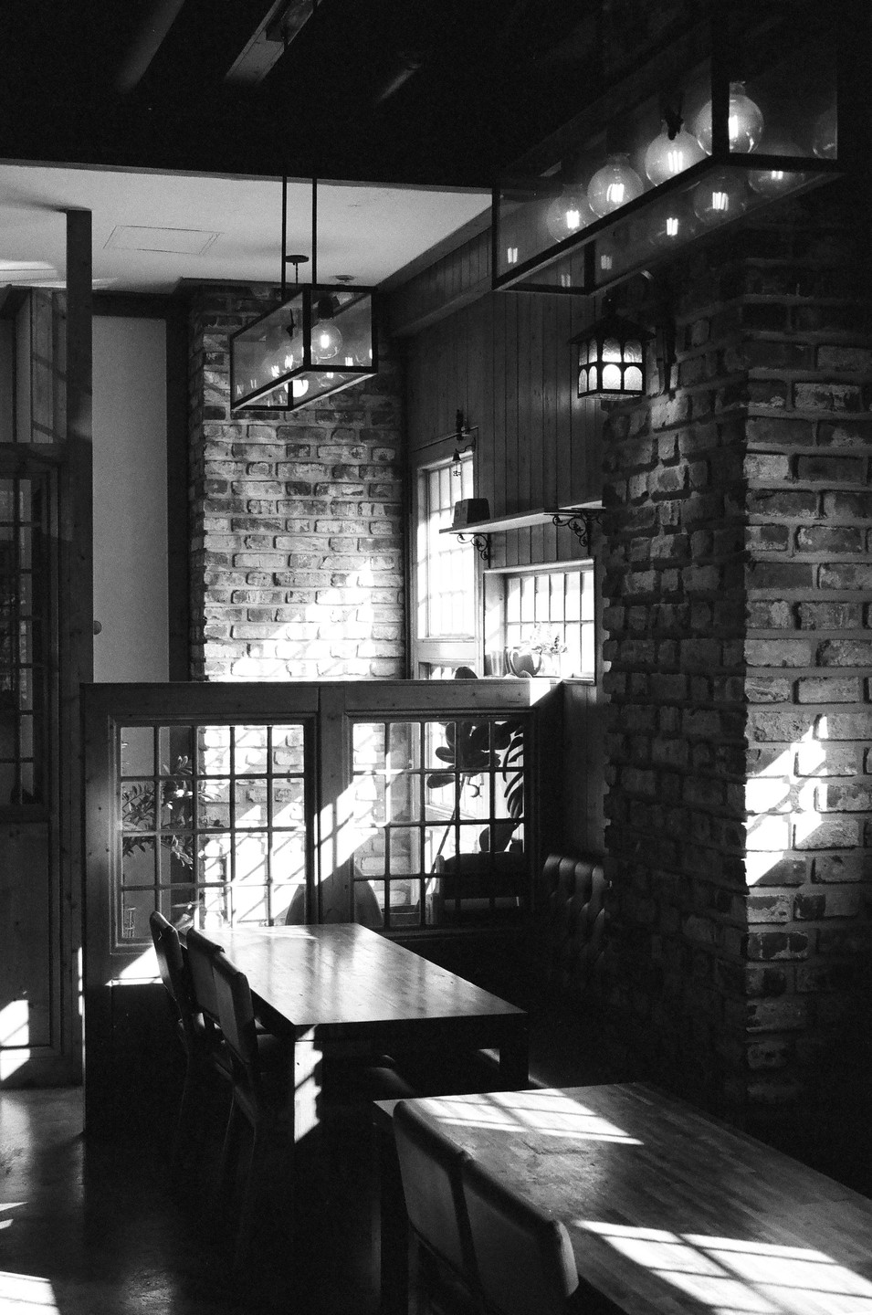 Sunlight streams into a quiet coffee shop with brick walls and wooden tables.