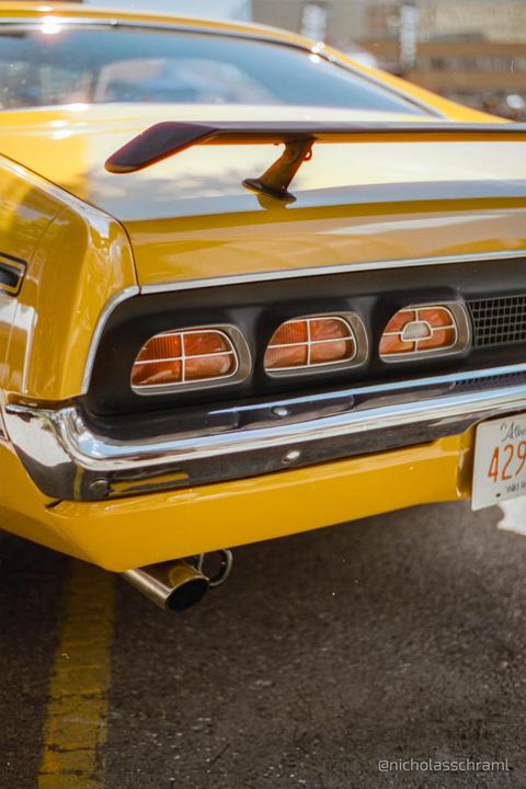 The rear of a yellow Mercury Cyclone is parked on asphalt with a license plate visible.