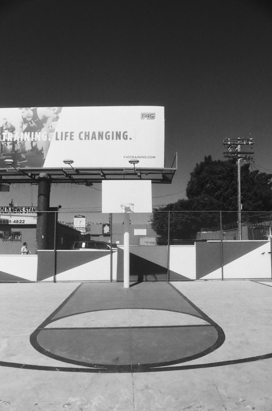 A basketball hoop stands on a court with a large billboard in the background.