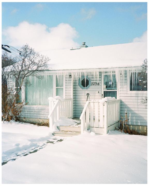 A house with icicles hanging from the roof is covered in snow.
