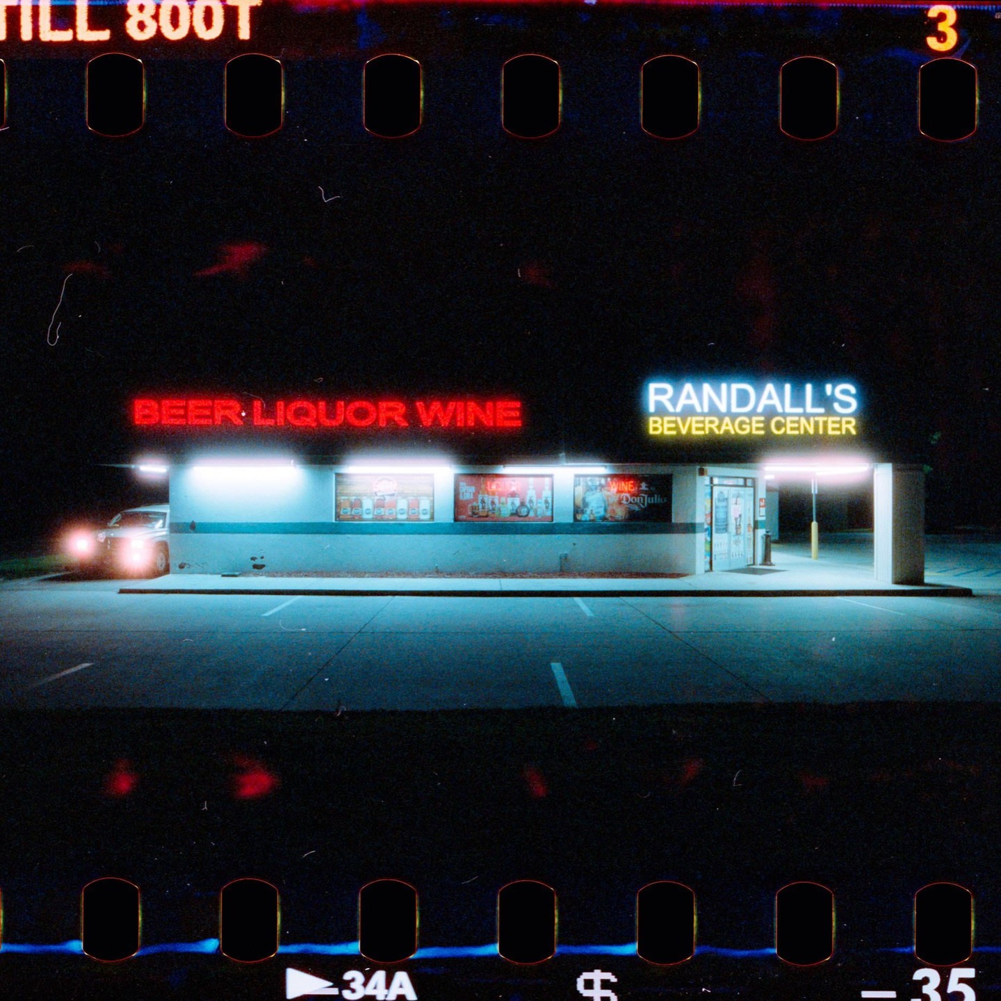 A car is parked in front of Randall's Beverage Center at night.