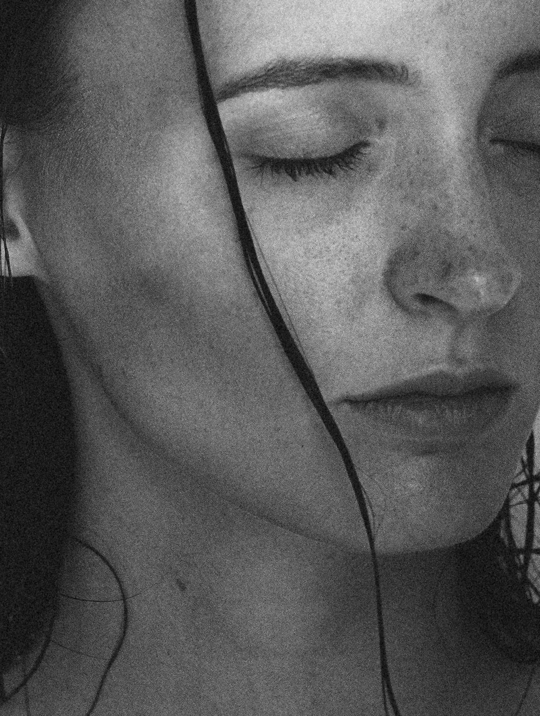 A woman with closed eyes and wet hair is shown in a close-up portrait.