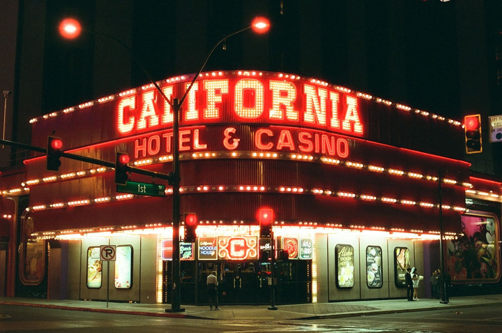 A large red neon sign for the California Hotel & Casino illuminates a street corner at night.